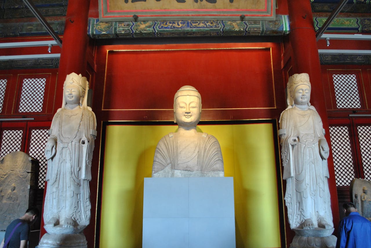 Buddha statues displayed inside a historic temple with ornate red and gold decor.
