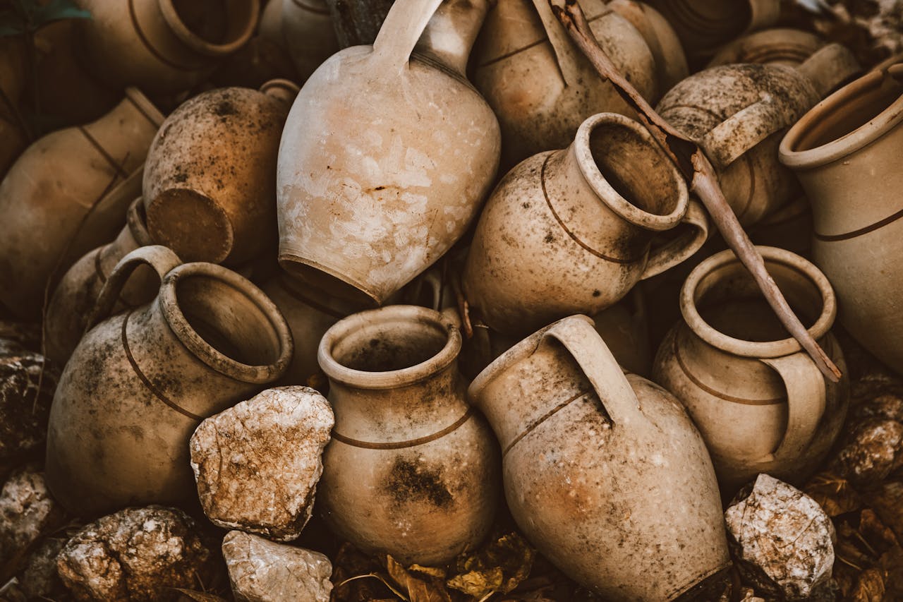 A collection of rustic earthenware jars arranged outdoors, showcasing a blend of history and craftsmanship.