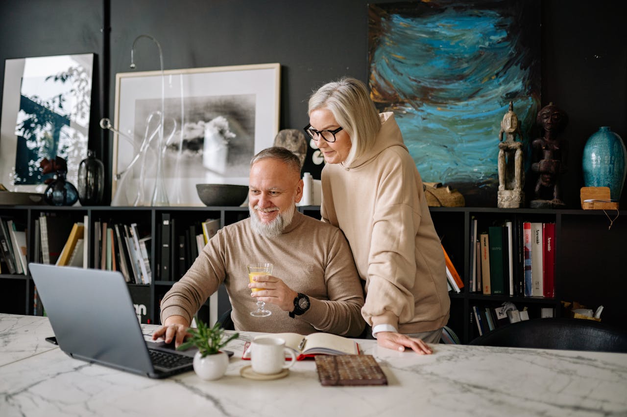 Elderly couple using a laptop at home, enjoying online activities and companionship.
